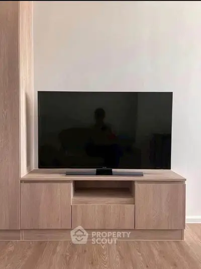 Modern living room with sleek wooden TV stand and large flat-screen TV, perfect for entertainment.