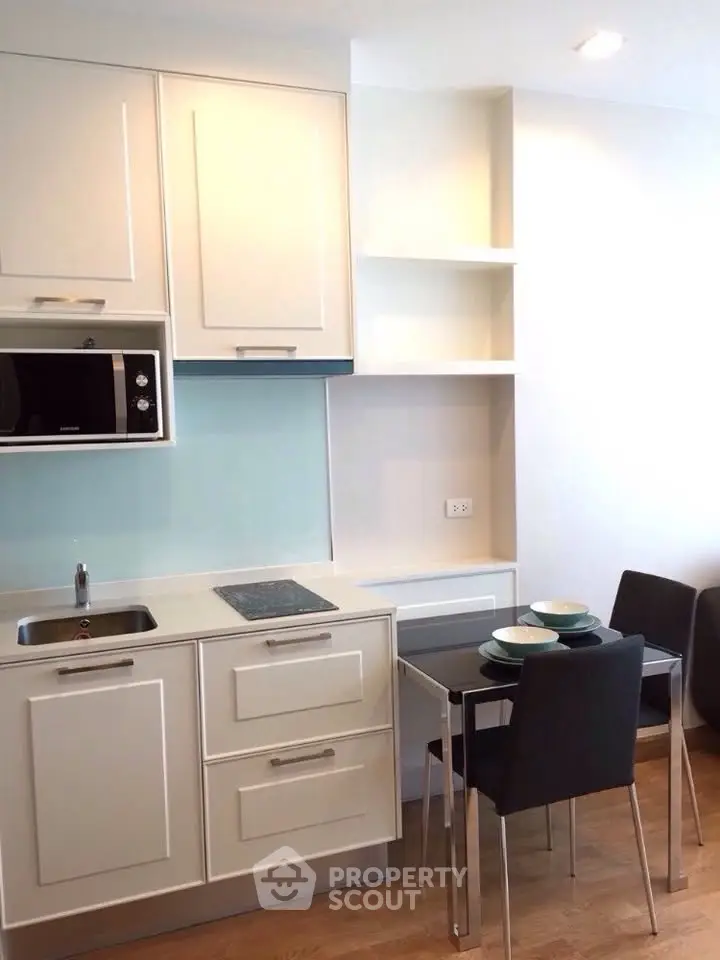 Modern kitchen with sleek cabinetry and dining area in a stylish apartment.