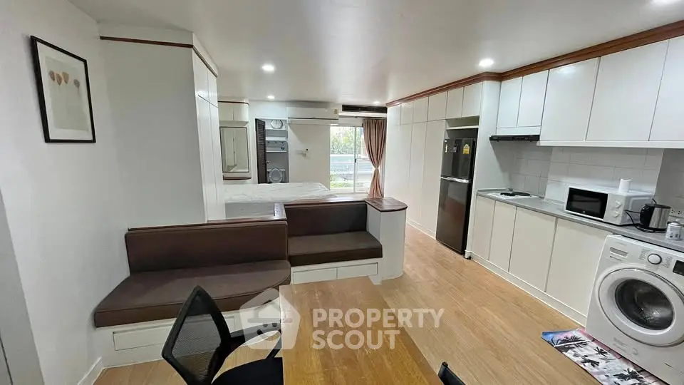Modern open-plan living space with kitchen, dining, and seating area featuring sleek appliances and wooden flooring.