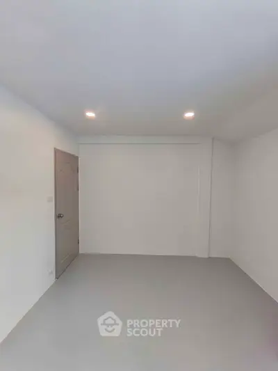 Spacious empty room with modern lighting and neutral walls, perfect for customization.