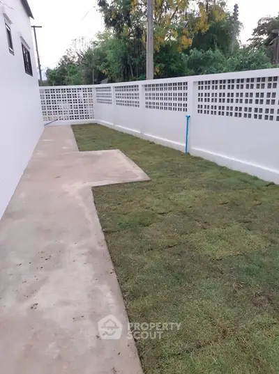 Charming backyard with freshly laid grass and modern white fence, perfect for outdoor relaxation.