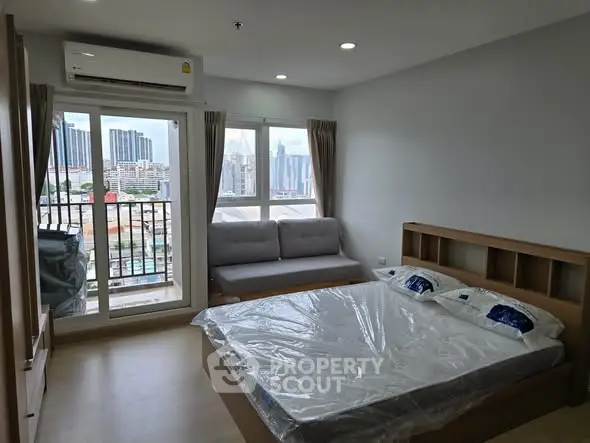 Modern bedroom with city view, featuring a cozy bed and a small balcony for urban living.