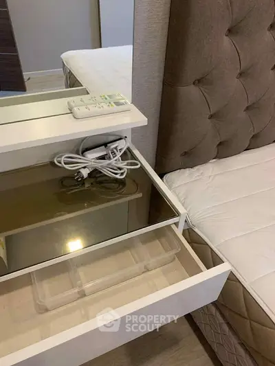 Modern bedroom with stylish headboard and sleek nightstand featuring built-in storage and remote control.