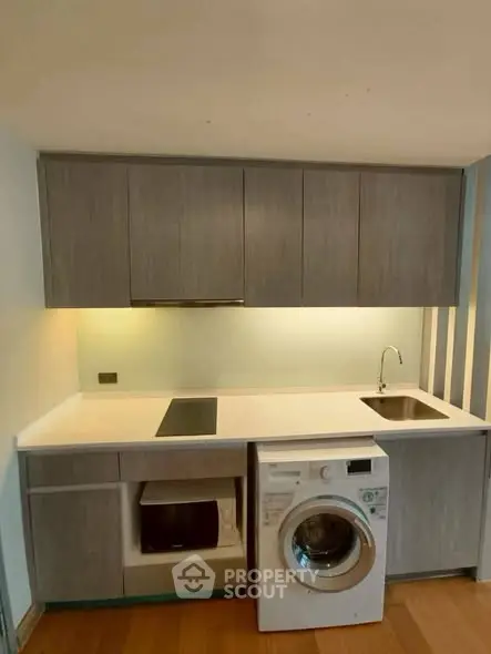 Modern kitchen with sleek cabinetry and built-in appliances including washing machine and stove.