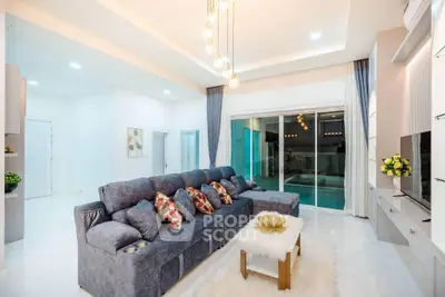 Luxurious living room with modern decor and pool view, featuring a plush sectional sofa and elegant lighting.