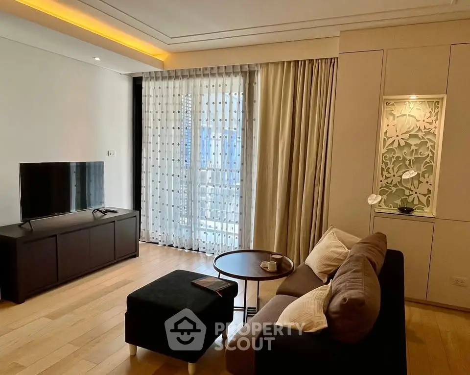 Modern living room with stylish decor, featuring a cozy sofa, flat-screen TV, and elegant curtains.