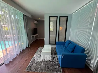 Modern living room with pool view, featuring a blue sofa and stylish decor.