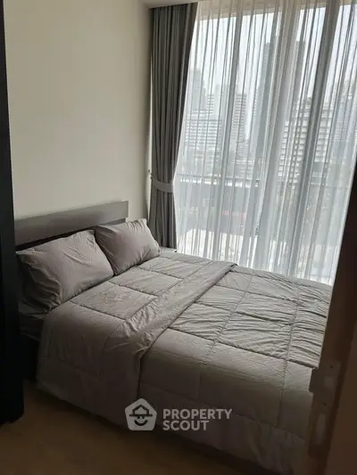 Cozy bedroom with city view, featuring a comfortable bed and floor-to-ceiling windows.