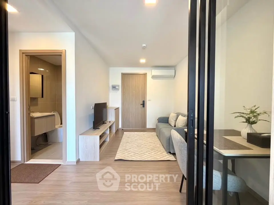 Modern living room with open layout and stylish decor, featuring a cozy seating area and a glimpse of the bathroom.
