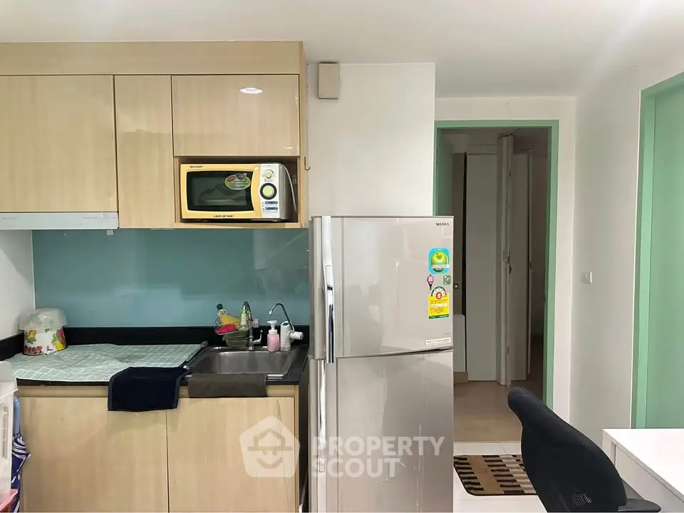 Modern kitchen with sleek cabinetry and stainless steel fridge in cozy apartment.