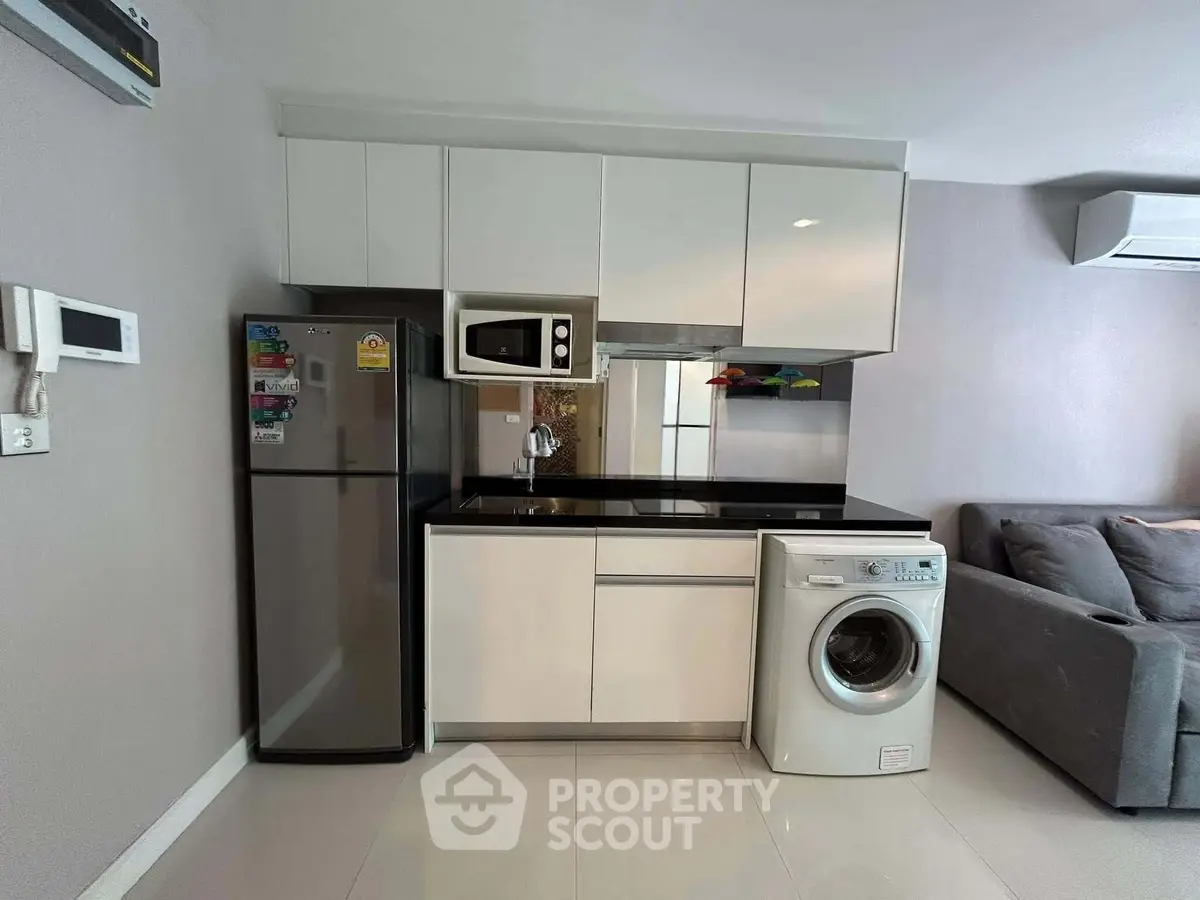 Modern kitchen with sleek appliances and cozy living area in a stylish apartment.