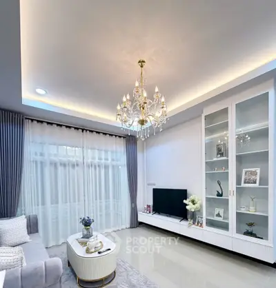 Elegant living room with chandelier, modern decor, and large window for natural light.