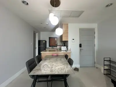 Modern dining area with marble table and sleek kitchen in open layout apartment.