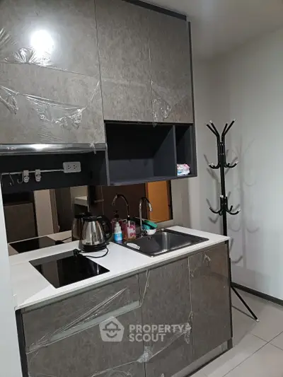 Modern compact kitchen with sleek cabinetry and built-in appliances in a stylish apartment.