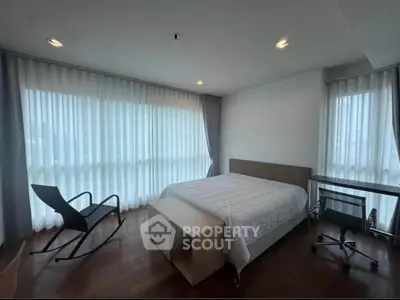 Spacious bedroom with modern furniture and large windows for natural light.