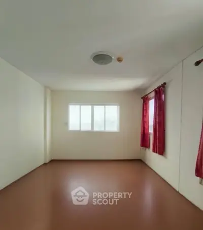 Spacious empty room with large window and red curtains, perfect for customization.