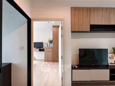 Modern apartment interior with sleek wooden cabinets and flat-screen TV, showcasing contemporary design and open layout.