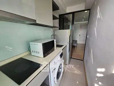 Modern kitchen with sleek appliances including washing machine and microwave in compact layout.