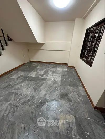 Spacious basement room with marble flooring and staircase access, ideal for storage or creative use.