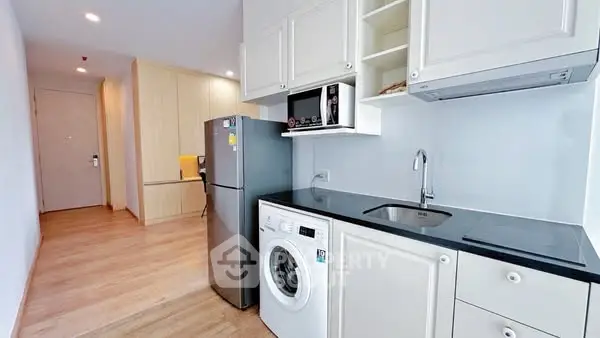 Modern kitchen with sleek appliances and wooden flooring in a stylish apartment.