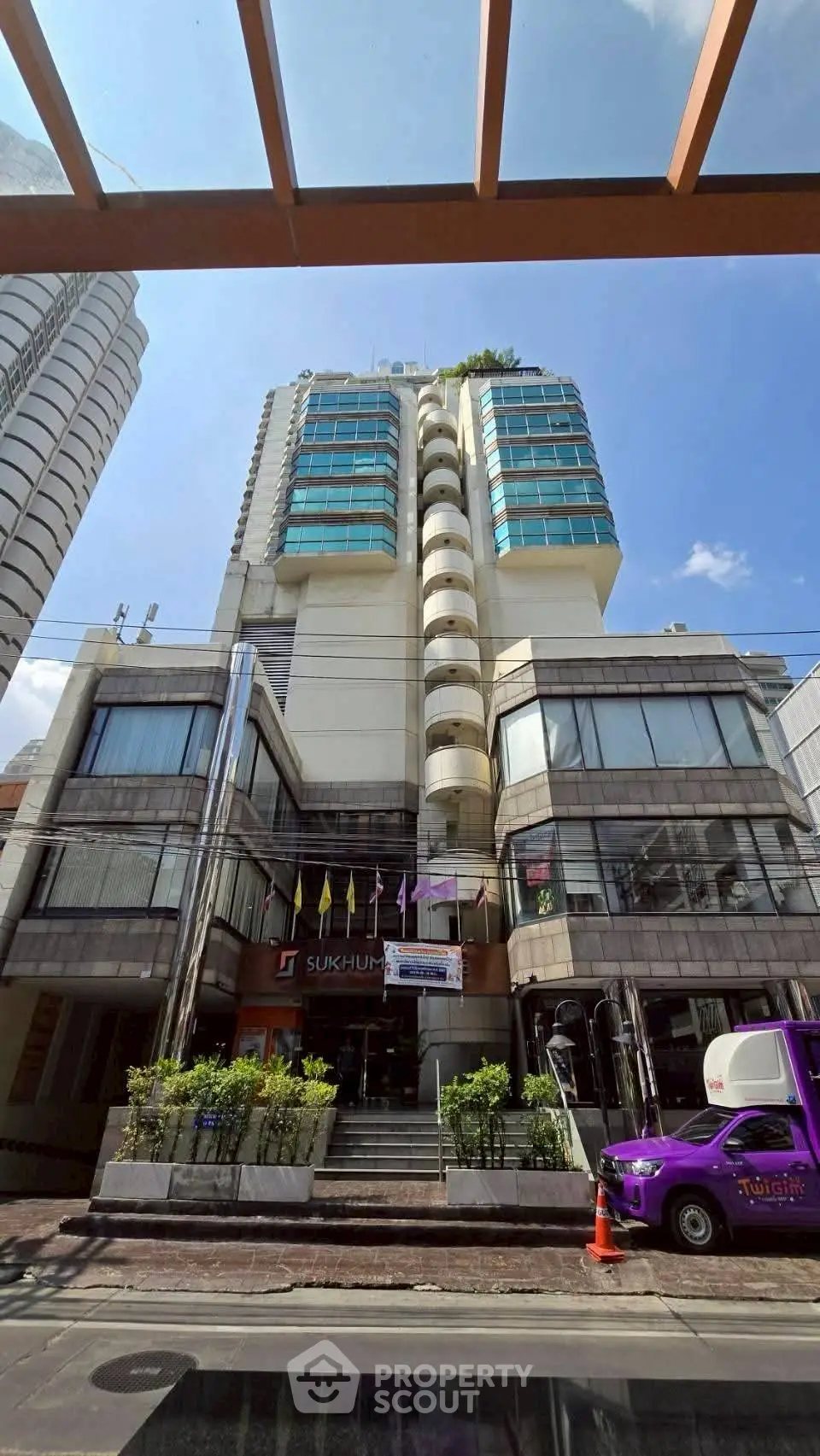 Modern high-rise building with glass facade and flags, showcasing urban architecture.