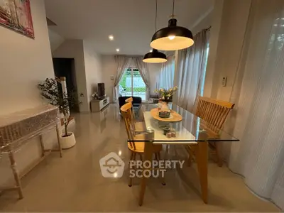 Modern dining area with glass table and stylish lighting in a cozy living space.