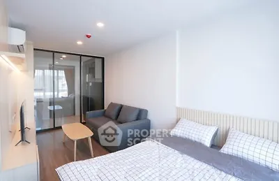 Modern studio apartment with cozy bedroom and living area, featuring sleek furniture and ample natural light.
