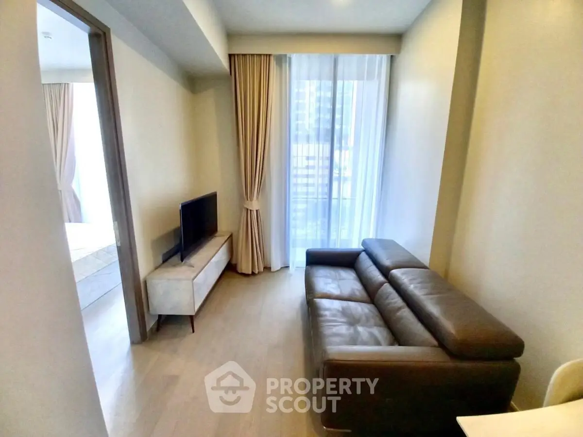 Modern living room with sleek leather sofa and natural light from large window.