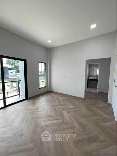 Spacious modern living room with large windows and elegant herringbone flooring.