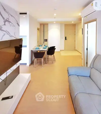 Modern living room with stylish decor and open dining area, featuring a sleek TV setup and comfortable seating.