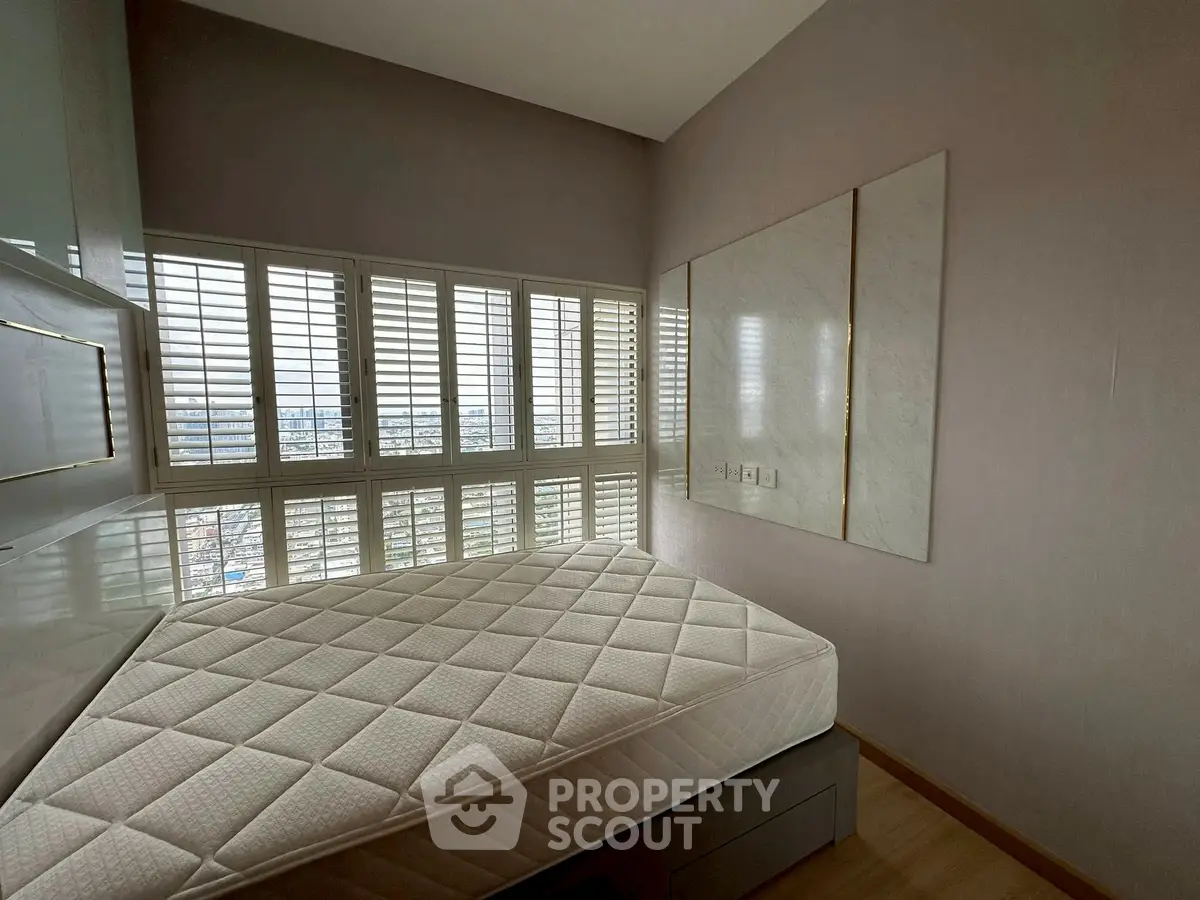 Modern bedroom with large windows and city view, featuring a comfortable mattress and sleek design.