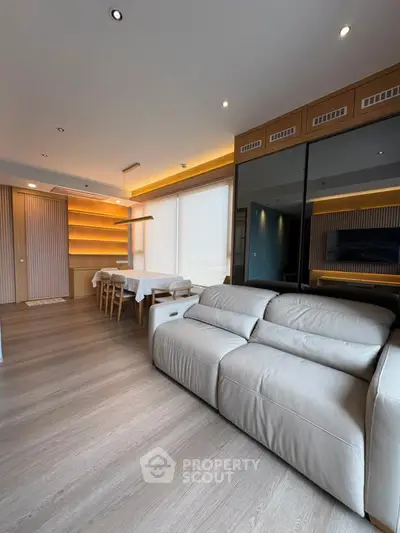 Modern living room with sleek design, featuring a cozy sofa and elegant dining area with ambient lighting.