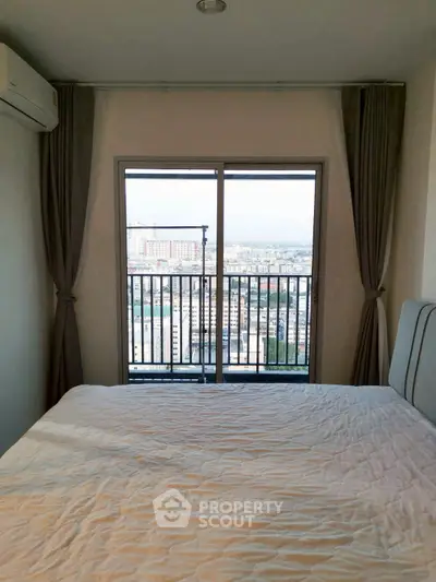 Cozy bedroom with city view from balcony, featuring modern decor and ample natural light.