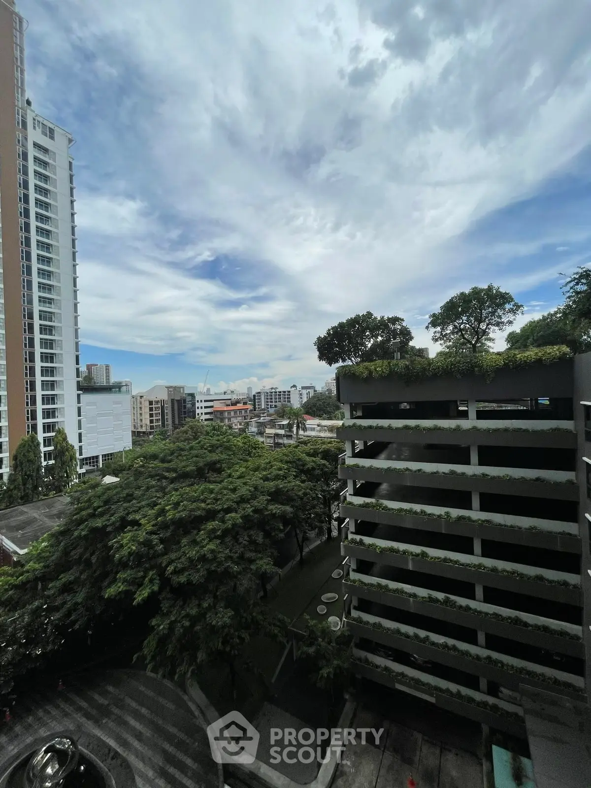 Stunning cityscape view from high-rise building with lush greenery and modern architecture.