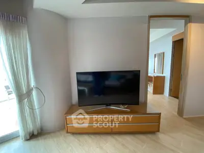 Modern living room with sleek TV stand and large flat-screen TV, featuring elegant wooden flooring.
