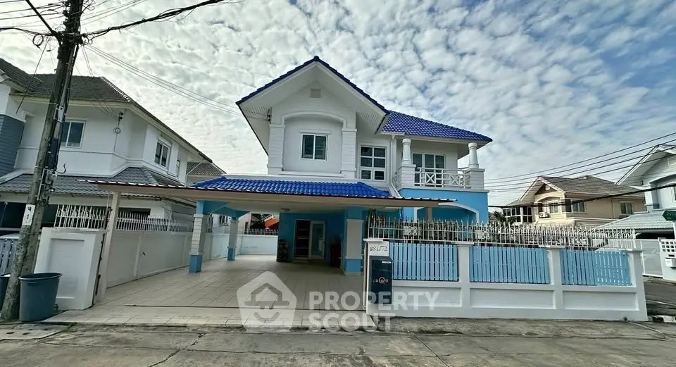 Charming two-story house with blue roof and spacious driveway in a serene neighborhood.
