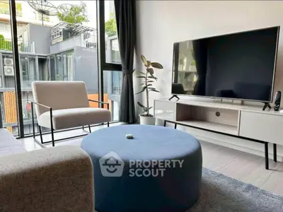 Modern living room with large TV, stylish furniture, and floor-to-ceiling windows offering natural light.