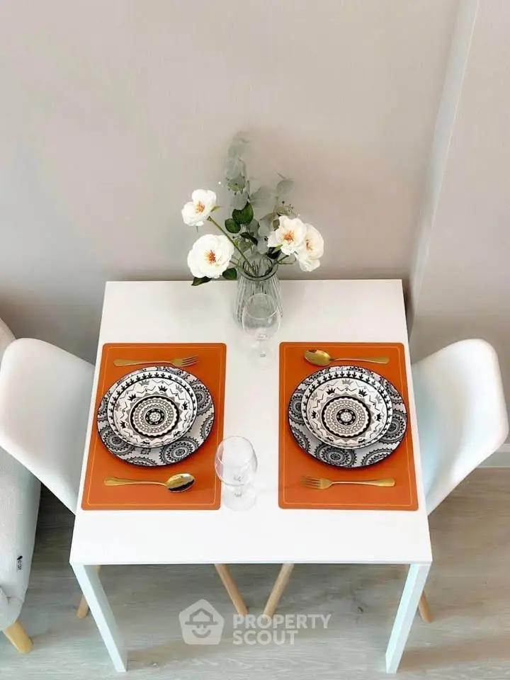 Chic dining setup with modern tableware and elegant floral centerpiece in a cozy apartment.