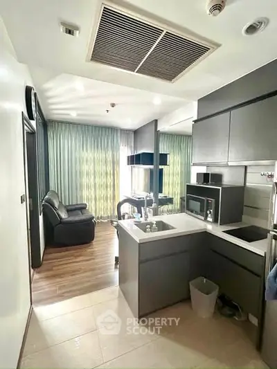 Modern open-layout kitchen with sleek cabinetry and cozy living area in stylish apartment.