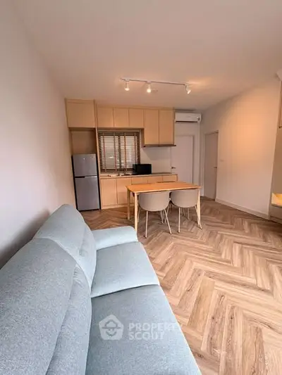 Modern living room with sleek kitchen and cozy seating area in open layout.
