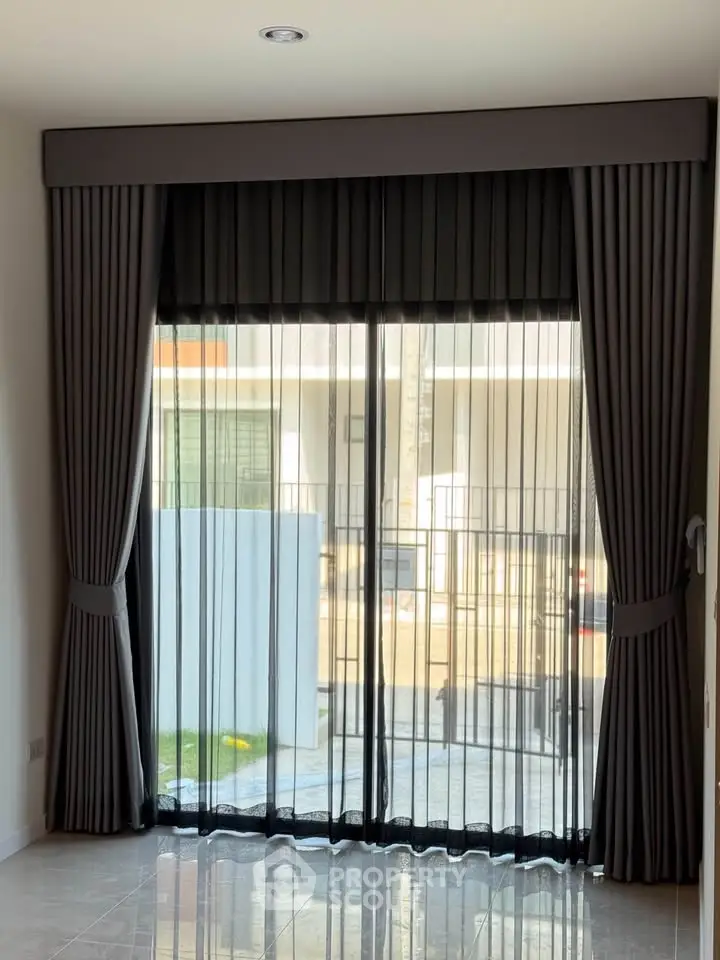 Elegant floor-to-ceiling window with sheer and blackout curtains in a modern home interior.