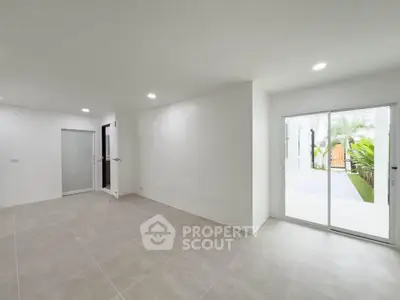 Spacious modern living room with sliding glass doors opening to a lush garden view.