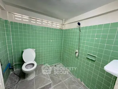 Spacious bathroom with green tiled walls and modern fixtures
