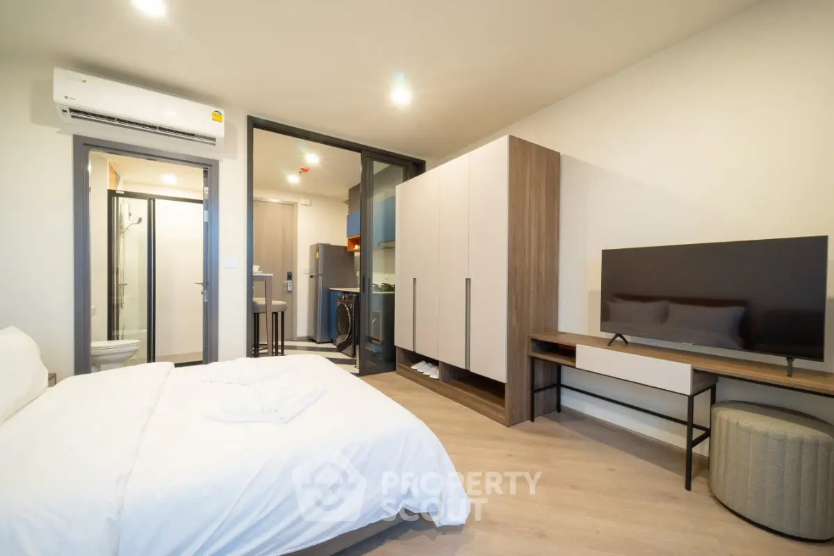 Modern studio apartment with open layout, featuring a cozy bedroom and sleek kitchen area.