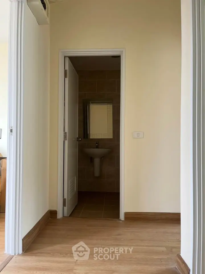 Minimalist hallway leading to a compact bathroom with modern fixtures.