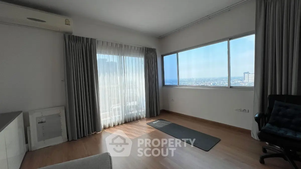 Bright living room with large windows and city view, featuring wooden flooring and modern decor.