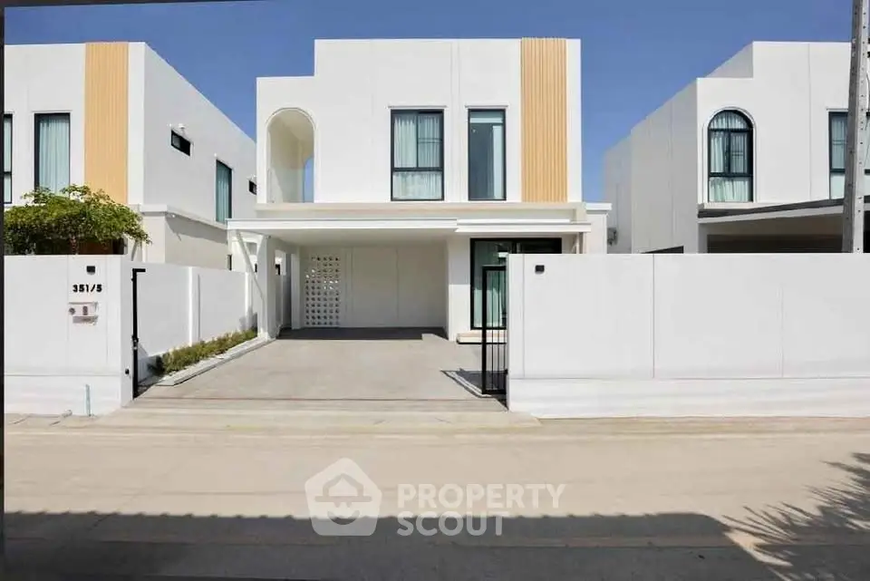 Modern white two-story house with minimalist design and spacious driveway in a serene neighborhood.