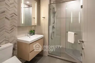 Modern bathroom with glass shower and sleek vanity in luxury apartment.