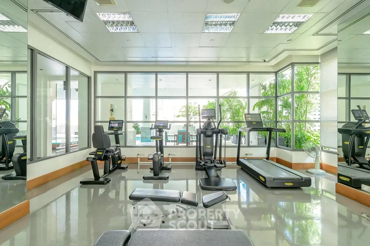 Spacious gym with modern equipment and large windows for natural light.