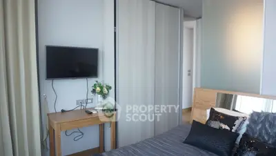 Modern bedroom with sleek design, featuring a wall-mounted TV and stylish wooden furniture.